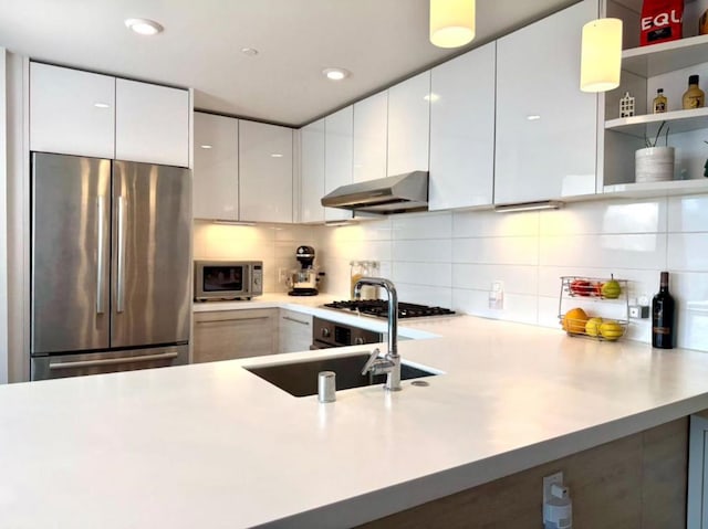 kitchen featuring sink, hanging light fixtures, stainless steel appliances, decorative backsplash, and white cabinets