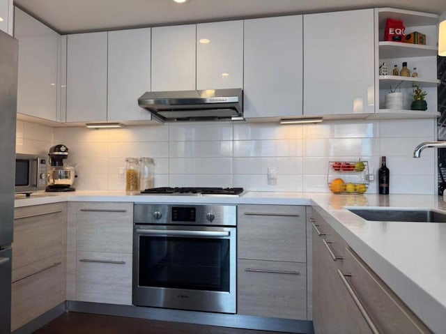 kitchen featuring white cabinetry, sink, backsplash, and appliances with stainless steel finishes