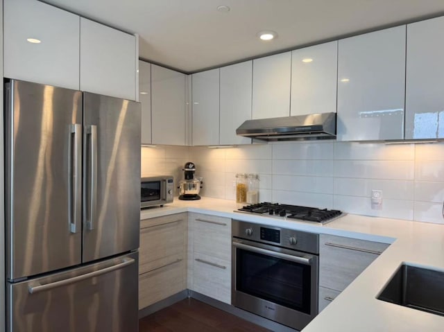 kitchen with white cabinetry, stainless steel appliances, dark hardwood / wood-style flooring, and tasteful backsplash