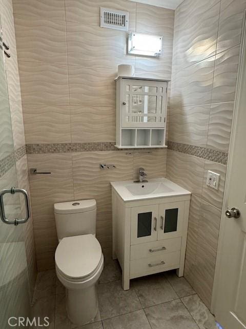 bathroom with vanity, tile walls, tile patterned floors, and toilet