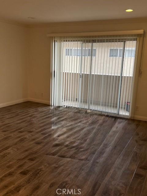 unfurnished room with ornamental molding and dark wood-type flooring