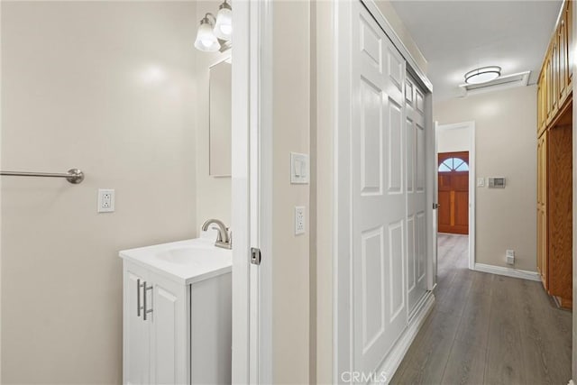 hall with a sink, baseboards, and dark wood-style flooring