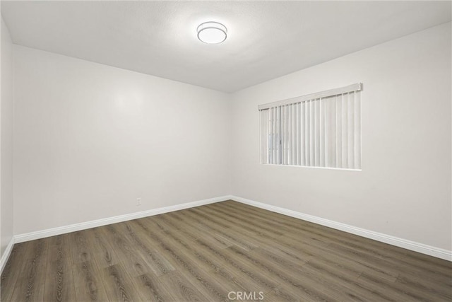 unfurnished room with dark wood-style flooring and baseboards