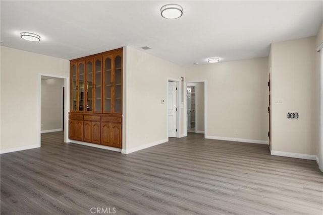 unfurnished room with dark wood finished floors, visible vents, and baseboards