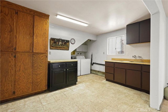 kitchen featuring washer / dryer, light countertops, a sink, and light floors