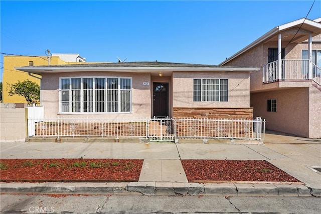 view of front facade with fence and stucco siding