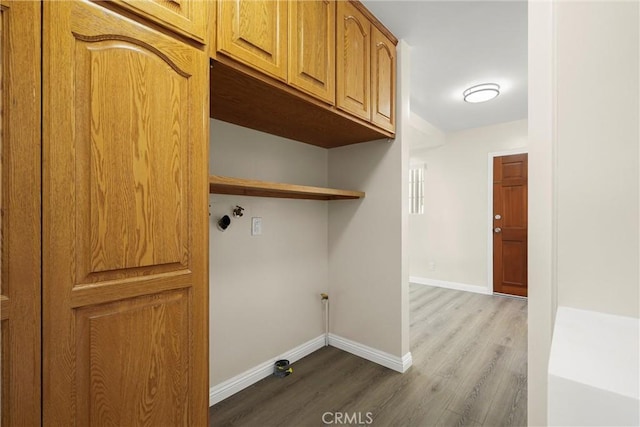 laundry area with wood finished floors, cabinet space, and baseboards