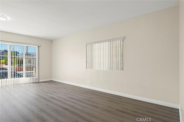 empty room featuring dark wood-type flooring and baseboards