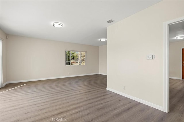 empty room featuring visible vents, baseboards, and wood finished floors