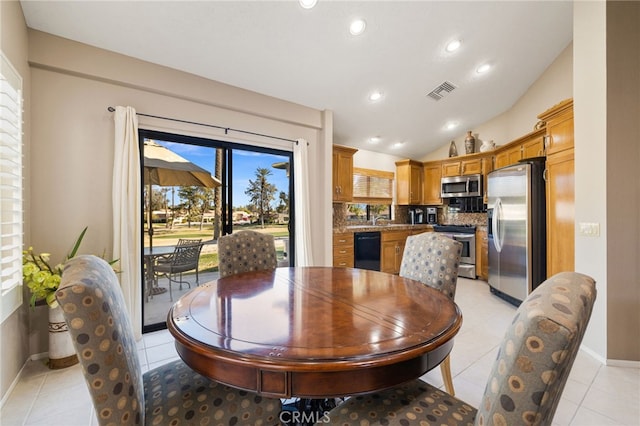 dining area with sink, vaulted ceiling, and light tile patterned floors