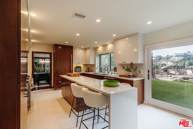 kitchen with sink, white cabinetry, tasteful backsplash, a center island, and a kitchen breakfast bar