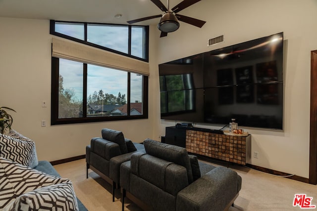 carpeted cinema room featuring a high ceiling and ceiling fan