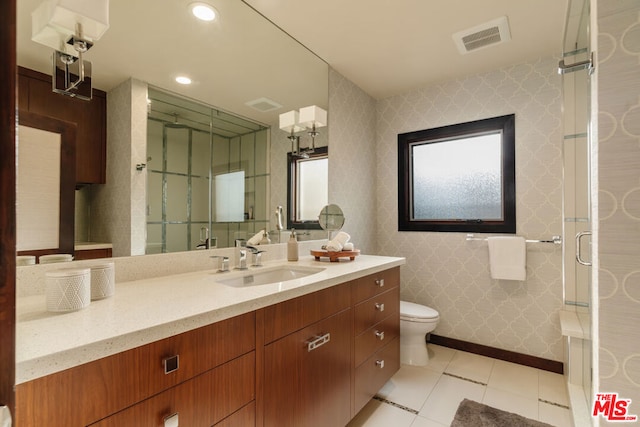 bathroom with vanity, a shower with shower door, tile patterned floors, and toilet