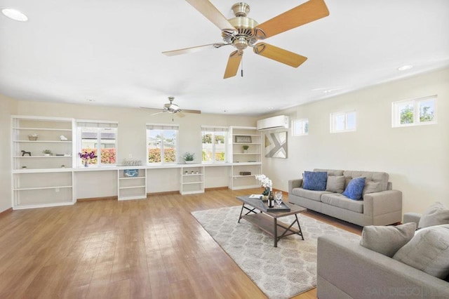 living room with a wall mounted AC and light wood-type flooring