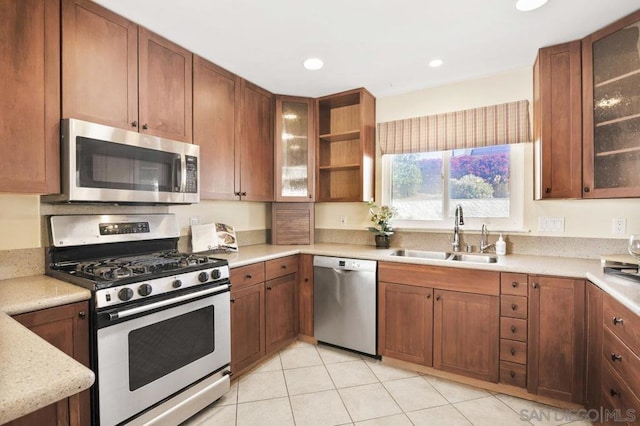 kitchen featuring light stone counters, sink, light tile patterned flooring, and appliances with stainless steel finishes