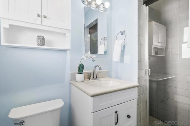 bathroom with vanity, a shower with door, and toilet