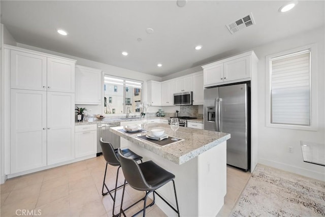 kitchen with appliances with stainless steel finishes, a kitchen breakfast bar, a center island, and white cabinets