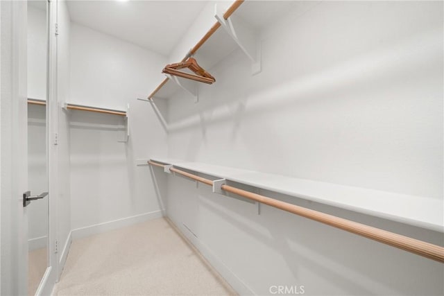 walk in closet featuring light colored carpet