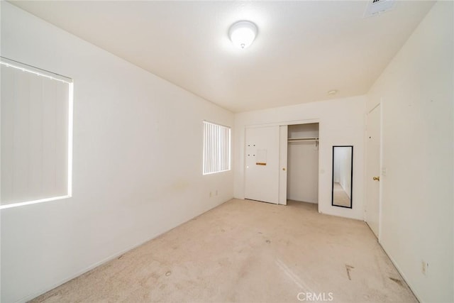 unfurnished bedroom with light colored carpet and a closet