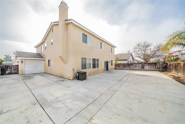 rear view of property with cooling unit and a garage