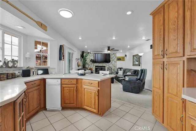 kitchen featuring ceiling fan, a stone fireplace, kitchen peninsula, and light tile patterned floors