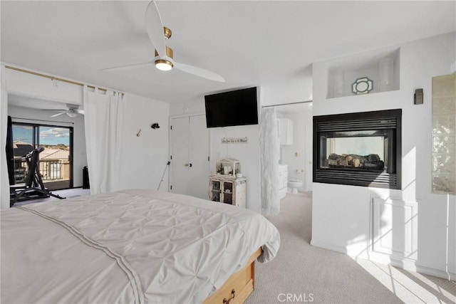 carpeted bedroom featuring connected bathroom, access to exterior, ceiling fan, and a multi sided fireplace