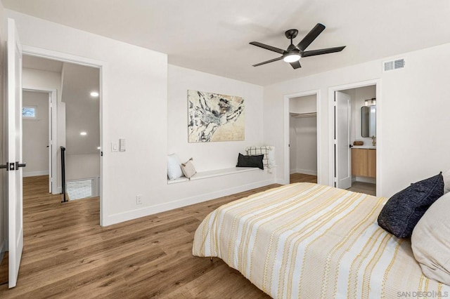 bedroom with ensuite bathroom, a spacious closet, a closet, hardwood / wood-style flooring, and ceiling fan