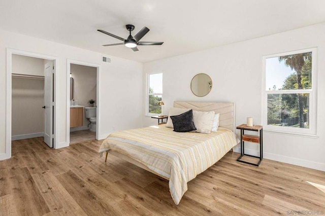 bedroom featuring ensuite bathroom, a walk in closet, a closet, ceiling fan, and light hardwood / wood-style floors