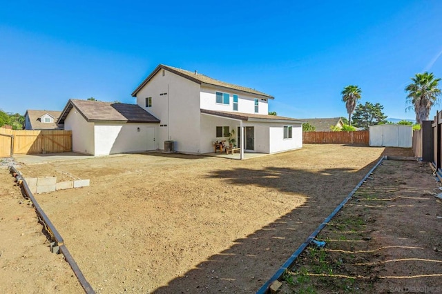 rear view of property with a shed, central AC, and a patio area