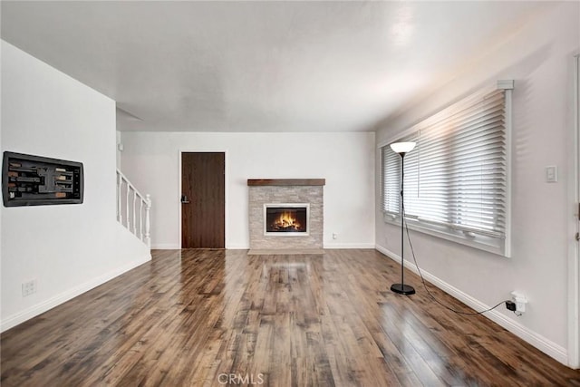 unfurnished living room featuring hardwood / wood-style flooring and a stone fireplace