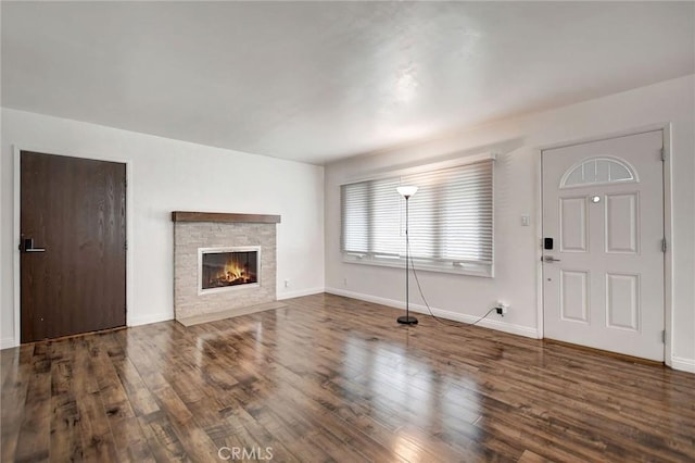 unfurnished living room with hardwood / wood-style flooring and a stone fireplace