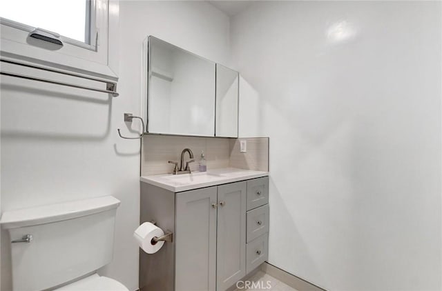 bathroom with vanity, backsplash, and toilet