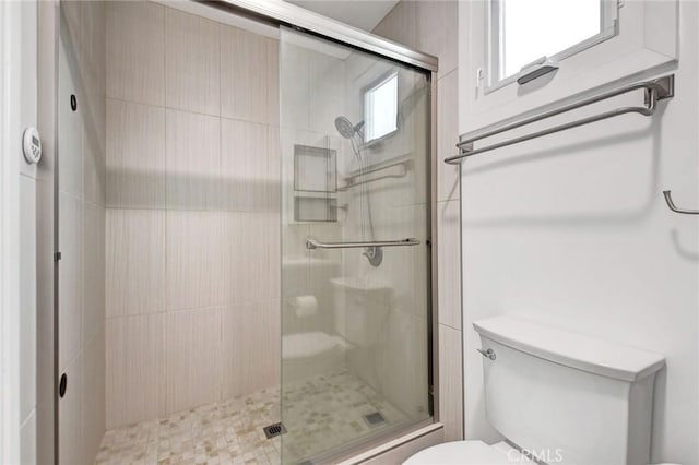 bathroom featuring toilet and a shower with shower door