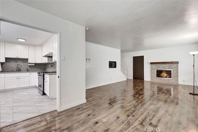 living room featuring a stone fireplace, sink, and light wood-type flooring