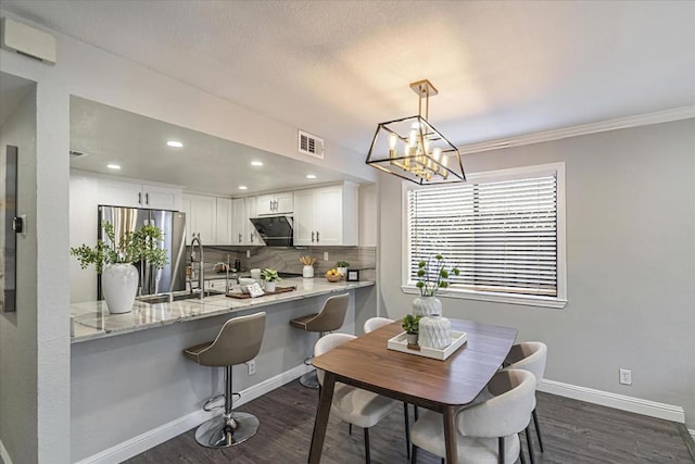 dining area featuring dark hardwood / wood-style flooring, a notable chandelier, and ornamental molding