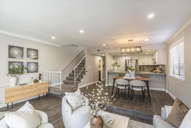 living room featuring an inviting chandelier, ornamental molding, and dark hardwood / wood-style flooring