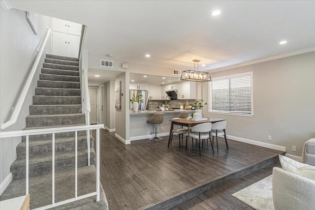 interior space featuring hardwood / wood-style flooring, crown molding, and an inviting chandelier