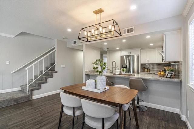 dining space featuring dark hardwood / wood-style flooring, a notable chandelier, and sink