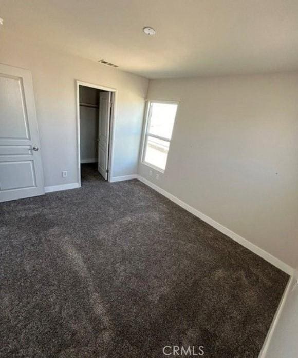 unfurnished bedroom featuring dark carpet and a closet