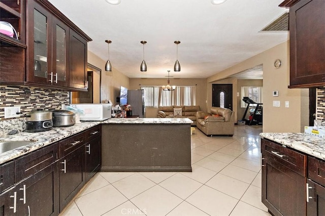 1230 Sunshine Dr, Barstow, CA 92311 - kitchen with dark brown cabinets, pendant lighting, light tile patterned floors, and decorative backsplash
