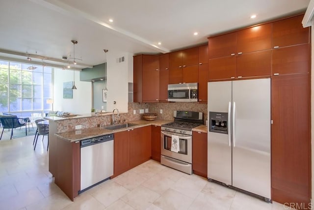 kitchen with sink, appliances with stainless steel finishes, kitchen peninsula, a wall of windows, and decorative backsplash