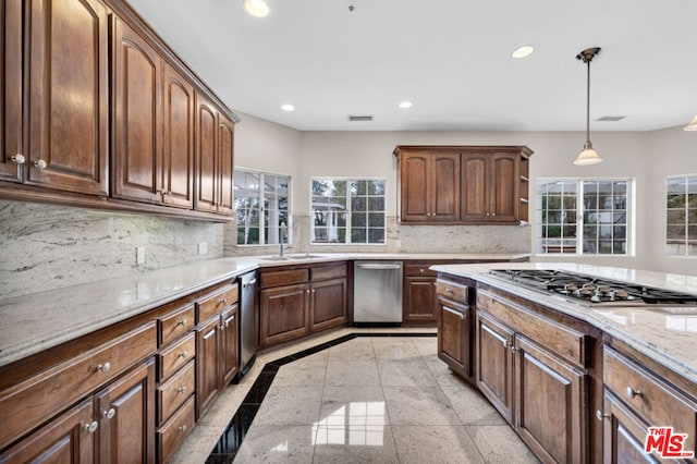 kitchen with decorative light fixtures, sink, decorative backsplash, light stone counters, and stainless steel appliances