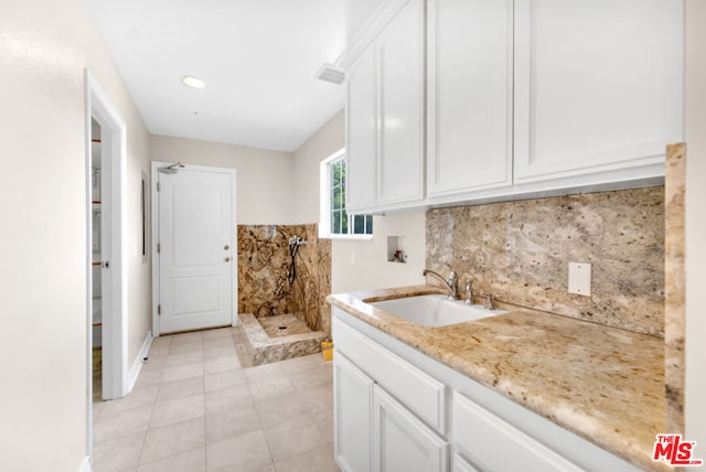 laundry area with cabinets, hookup for a washing machine, sink, and light tile patterned floors