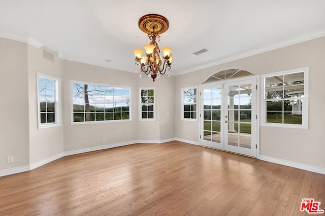 unfurnished dining area featuring a notable chandelier, crown molding, light hardwood / wood-style floors, and french doors