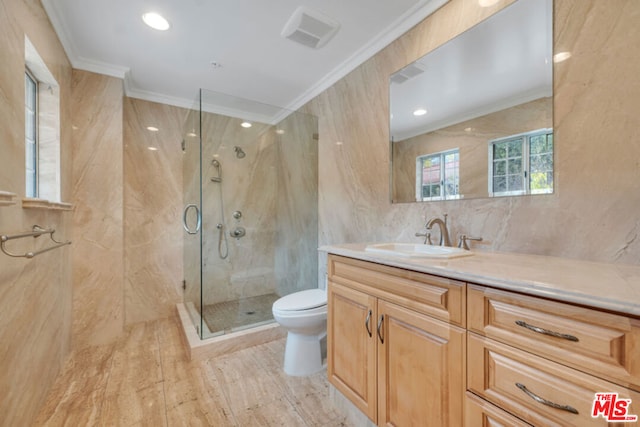 bathroom featuring toilet, crown molding, tile walls, vanity, and a shower with door