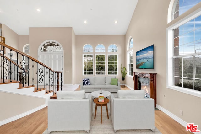 living room with a towering ceiling and light wood-type flooring