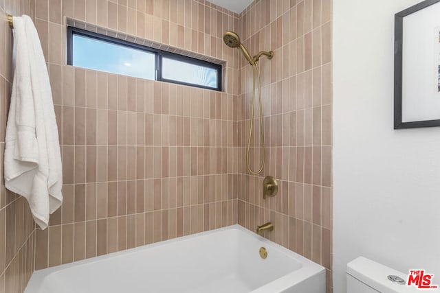 bathroom featuring tiled shower / bath combo and toilet