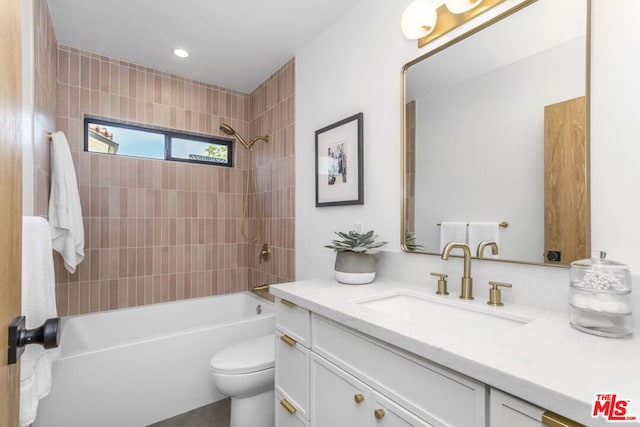 full bathroom featuring vanity, tiled shower / bath, and toilet