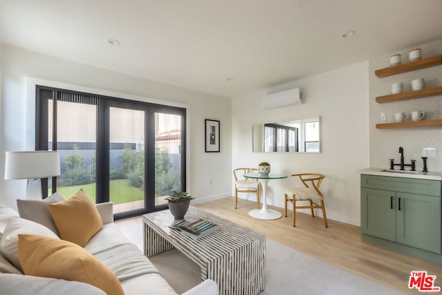 living room with sink, a wall mounted air conditioner, and light hardwood / wood-style floors