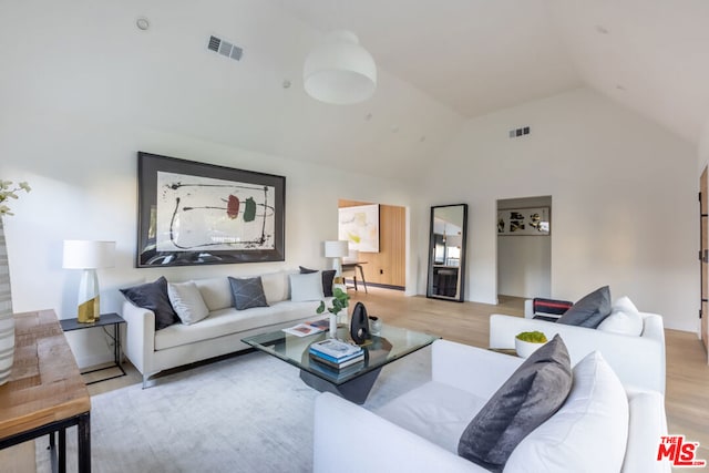 living room featuring high vaulted ceiling and light hardwood / wood-style floors